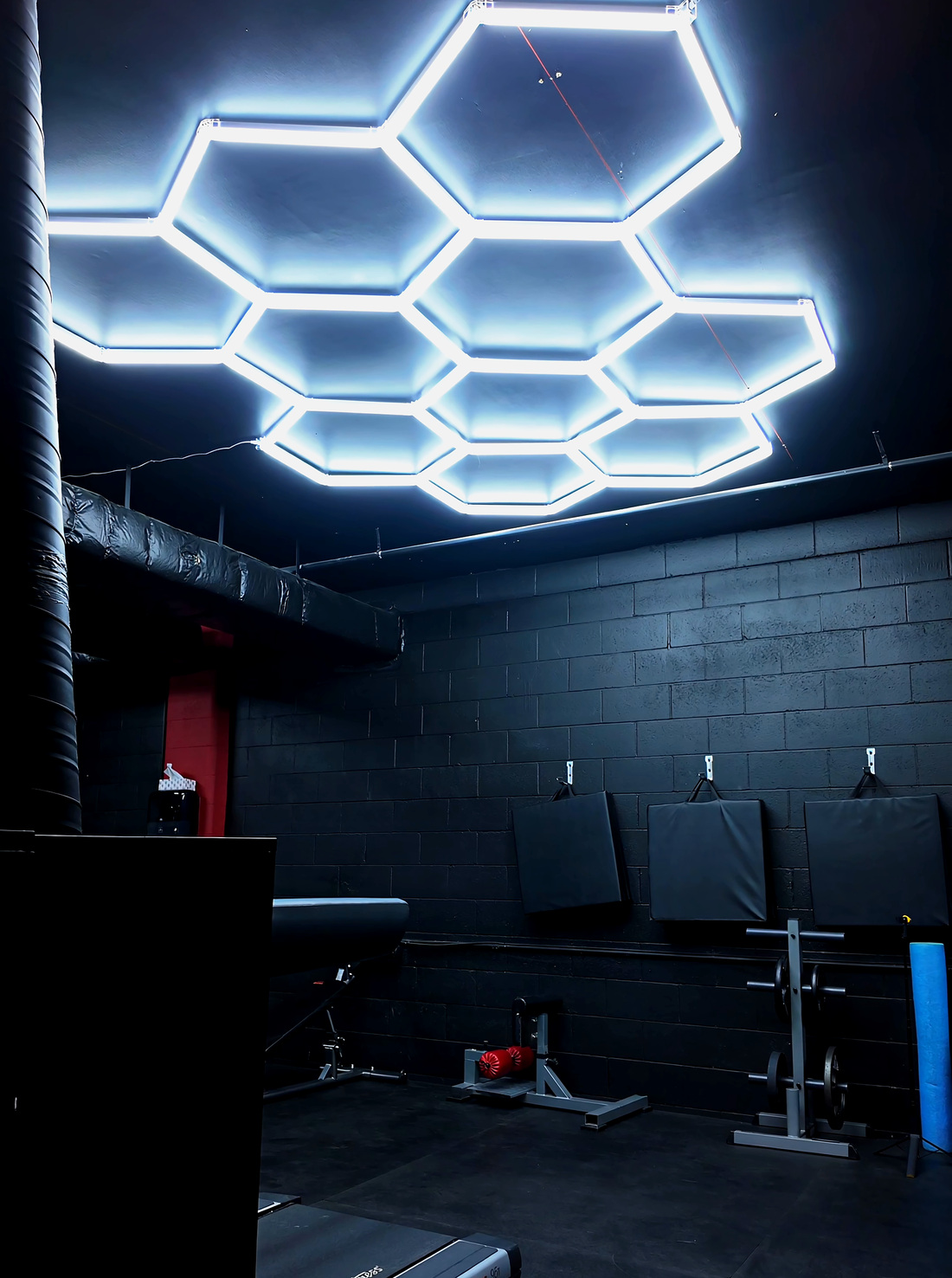The upstairs cardio and posing area at Legacy Athletix under the hexagon LED lighting grids